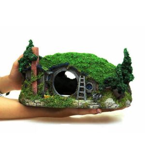 Hand-held Moss-covered Miniature Hobbit House with a Round Doorway, Ladder, Chimney, and Trees on a Grassy Hillside.